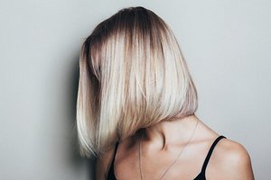 Blonde woman with a shiny mid-length bob with dark roots